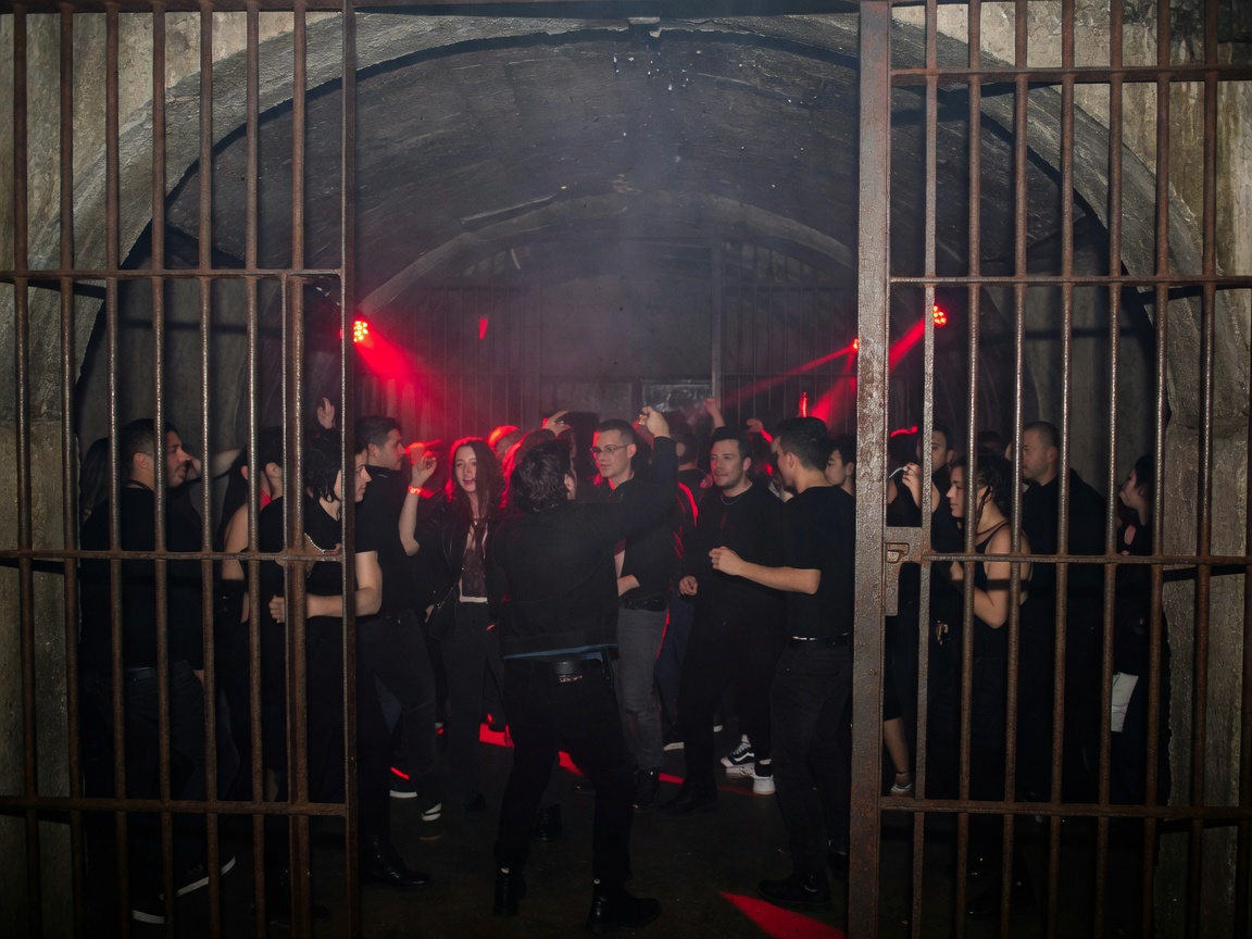 Subterranean vault club in Berlin with iron cage bars and red strobe lights